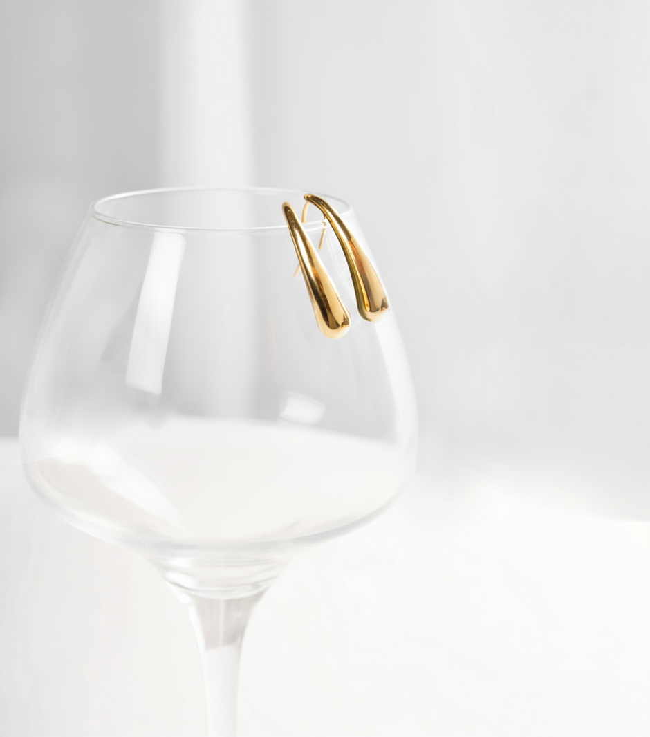 Clear glass vase with green leaves and white flower on a white background